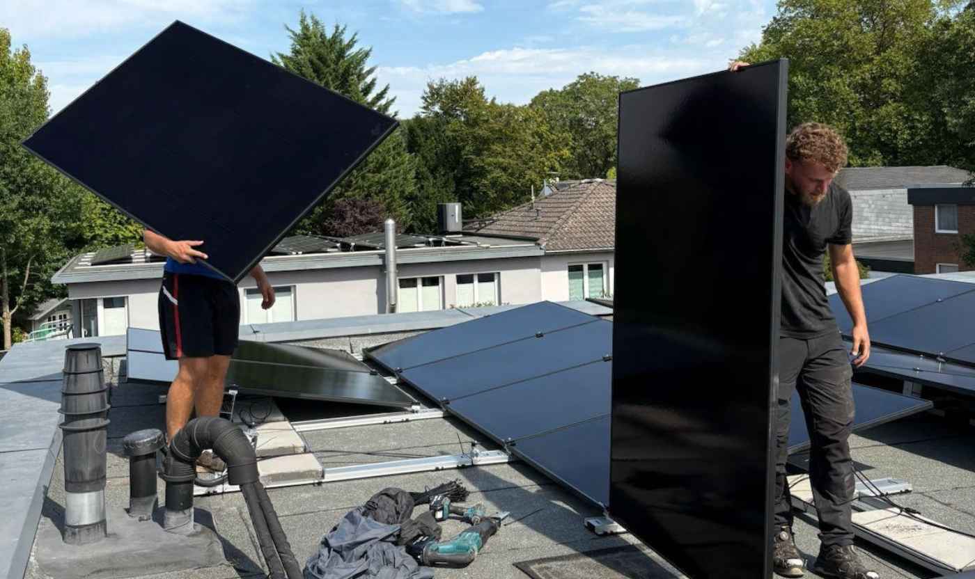 Zwei Monteure tragen Solarmodule während der Installation einer Photovoltaikanlage für Solar in Krefeld.