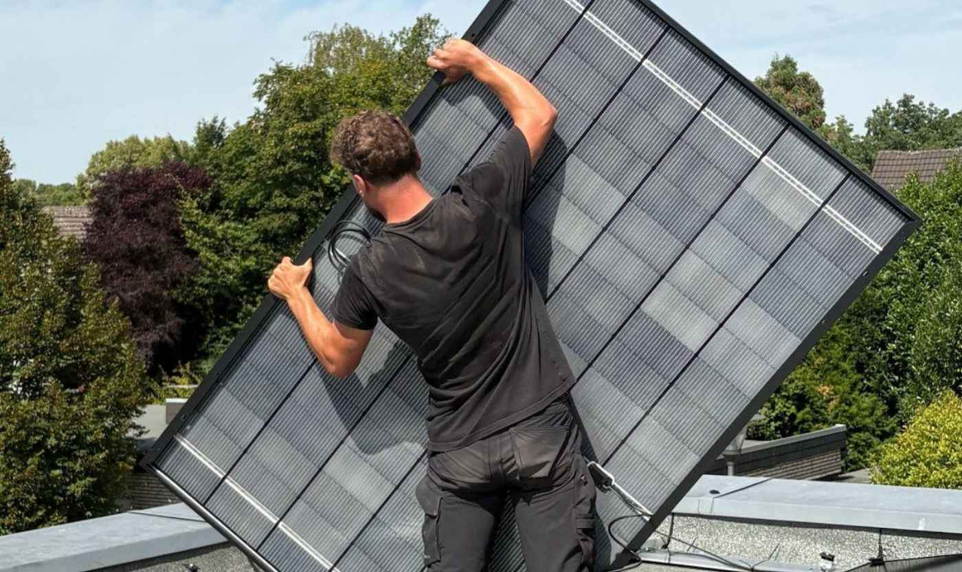 Ein Monteur richtet ein Solarmodul auf dem Flachdach für die Installation einer Solar-Anlage in Krefeld aus.